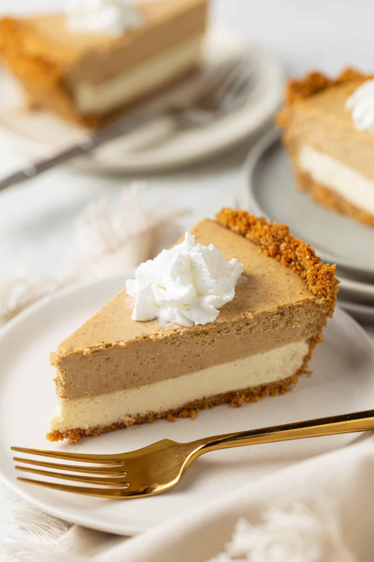 A piece of pumpkin cheese cake on a plate, with whipped Cream.