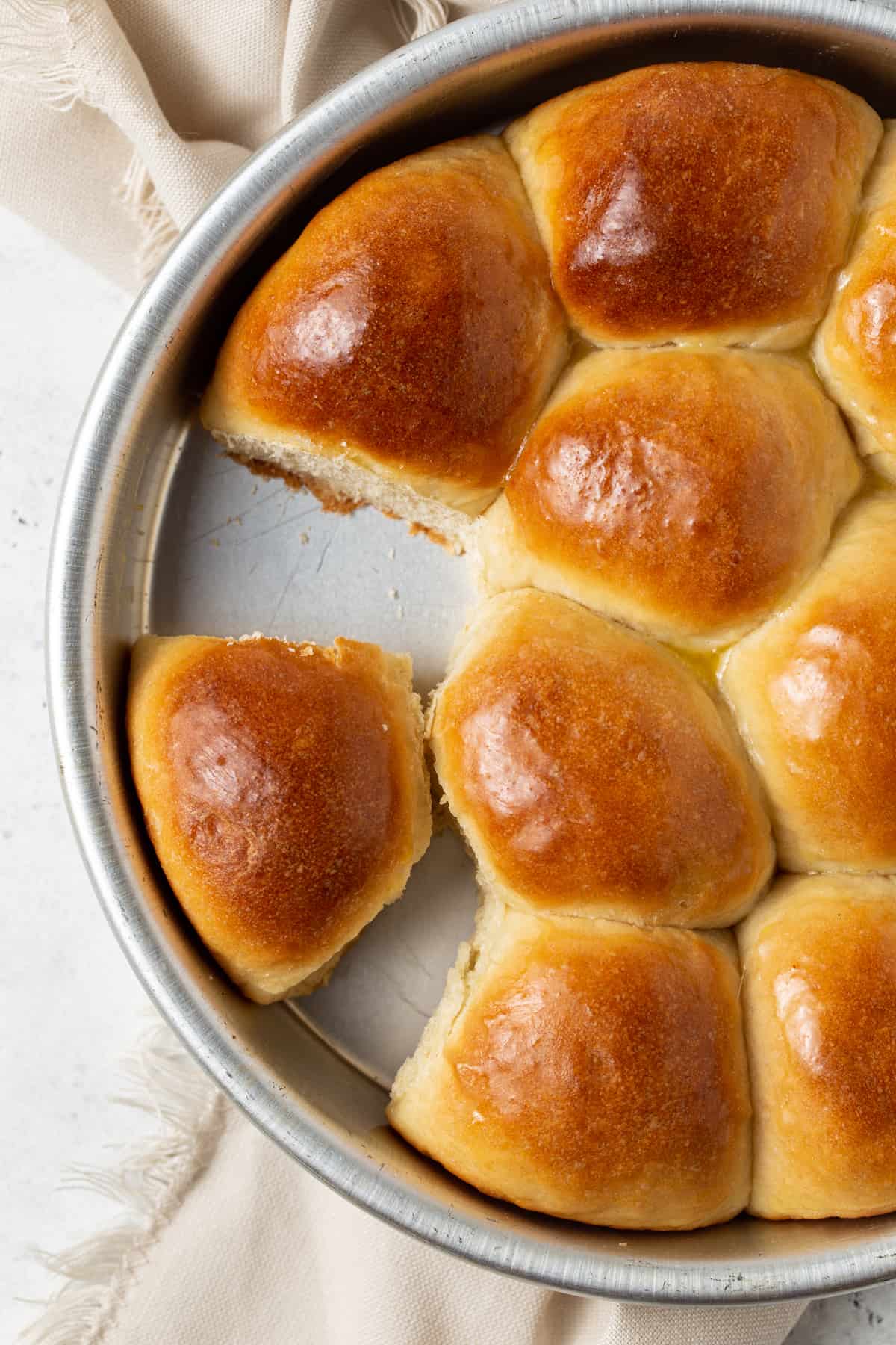 Cake pan filled with dinner rolls with one roll missing. 