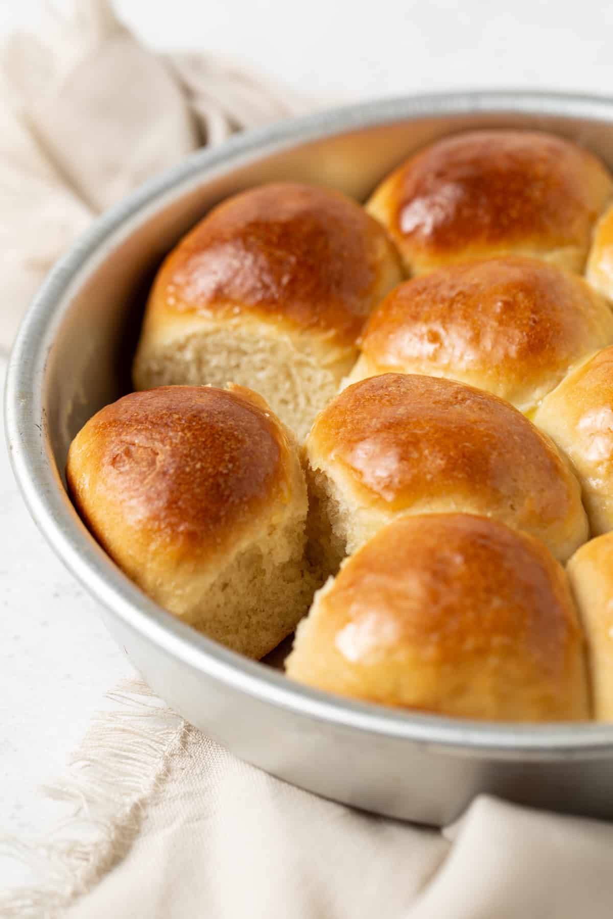 Baked rolls in a cake pan with one roll missing. 