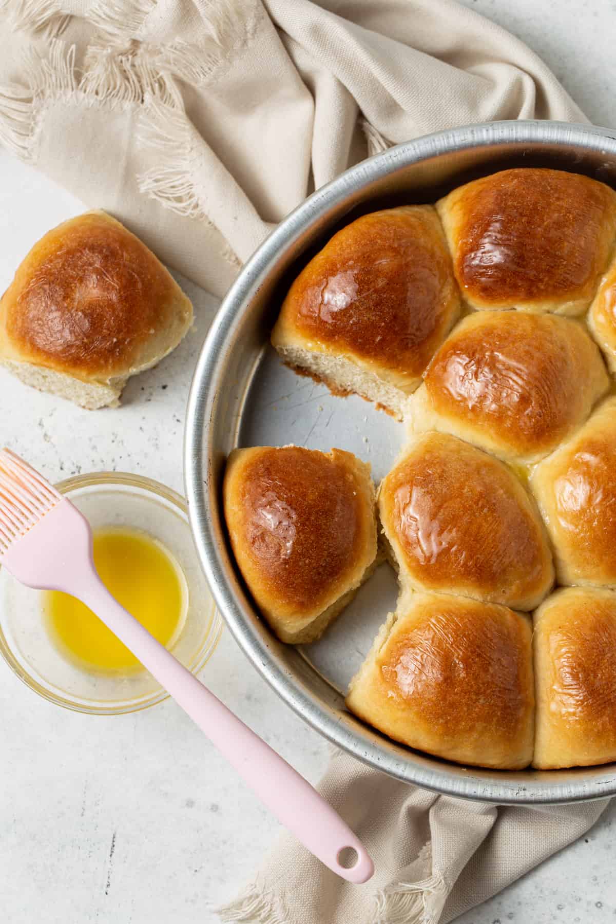 Baked rolls in cake pan with pastry brush and melted butter.