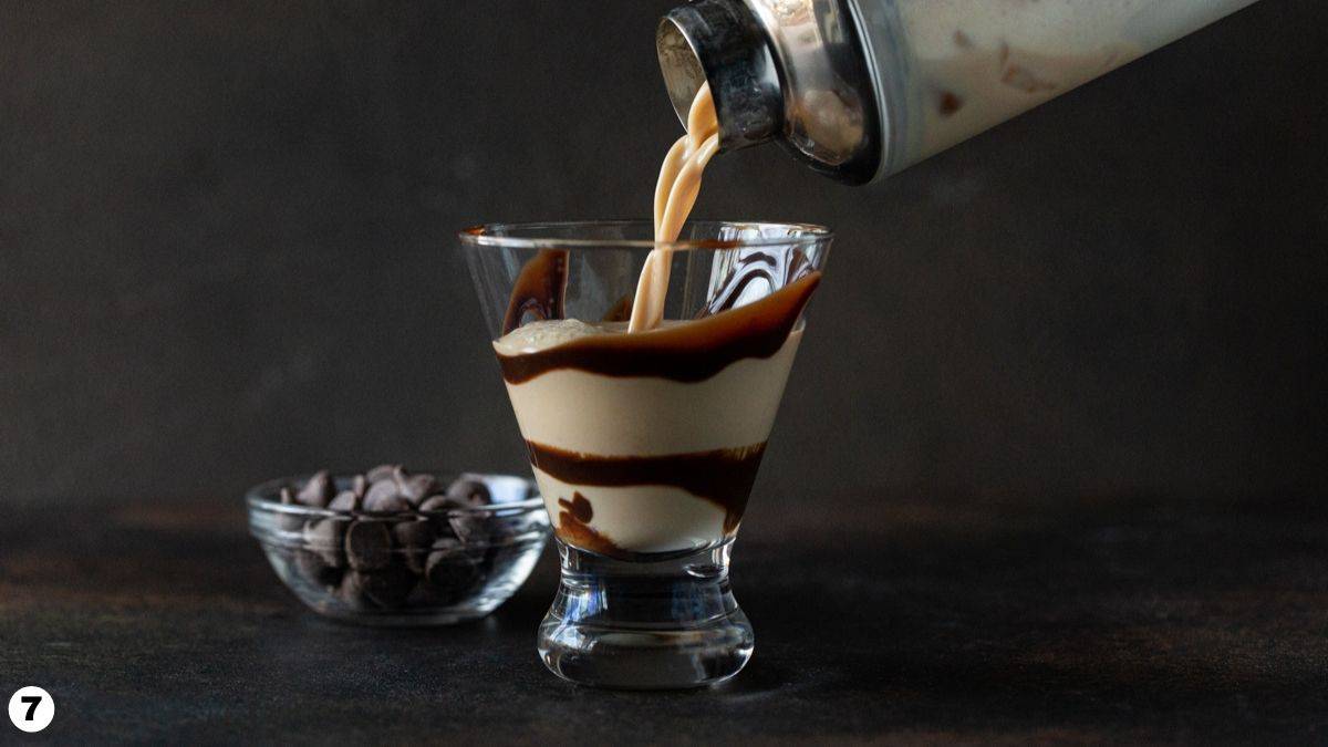Shaker pouring chocolate martini into chocolate swirled glass. 
