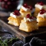 puff pastry with brie and cranberrry on wooden board.