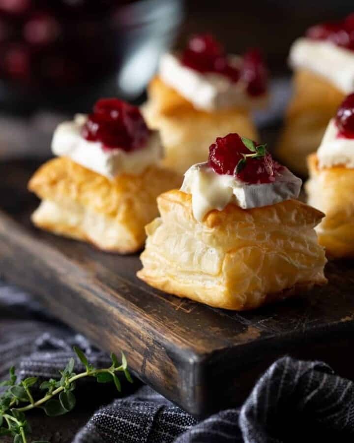 puff pastry with brie and cranberrry on wooden board.