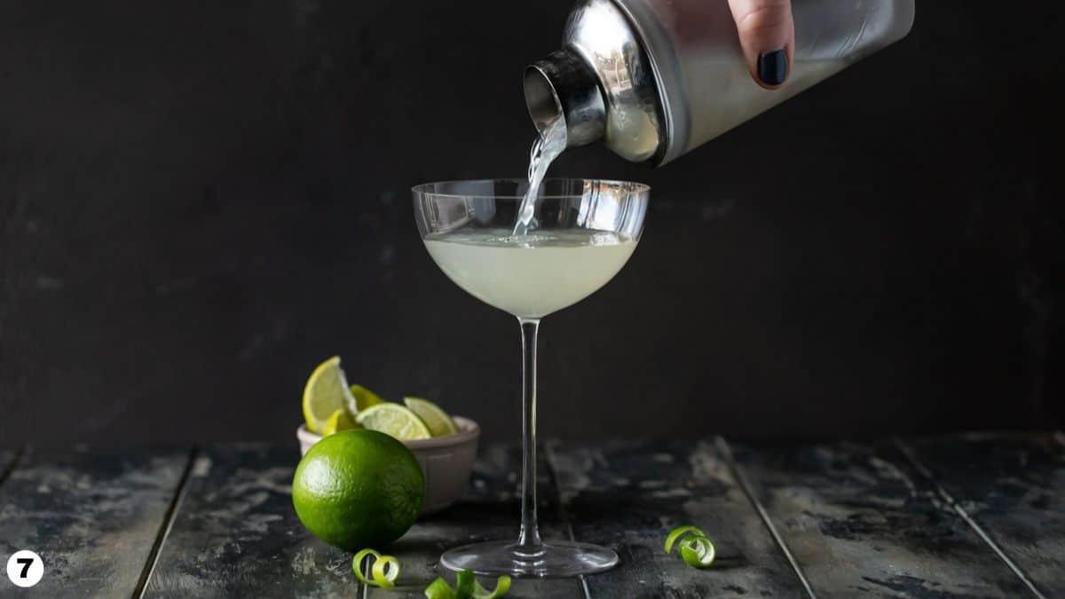 person pouring contents of cocktail shaker into glass.