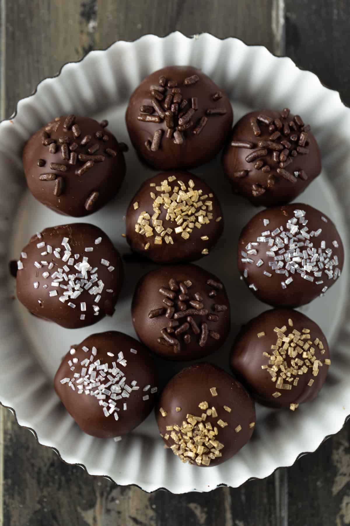 Chocolate dipped truffles in a small white metal fluted tart pan.