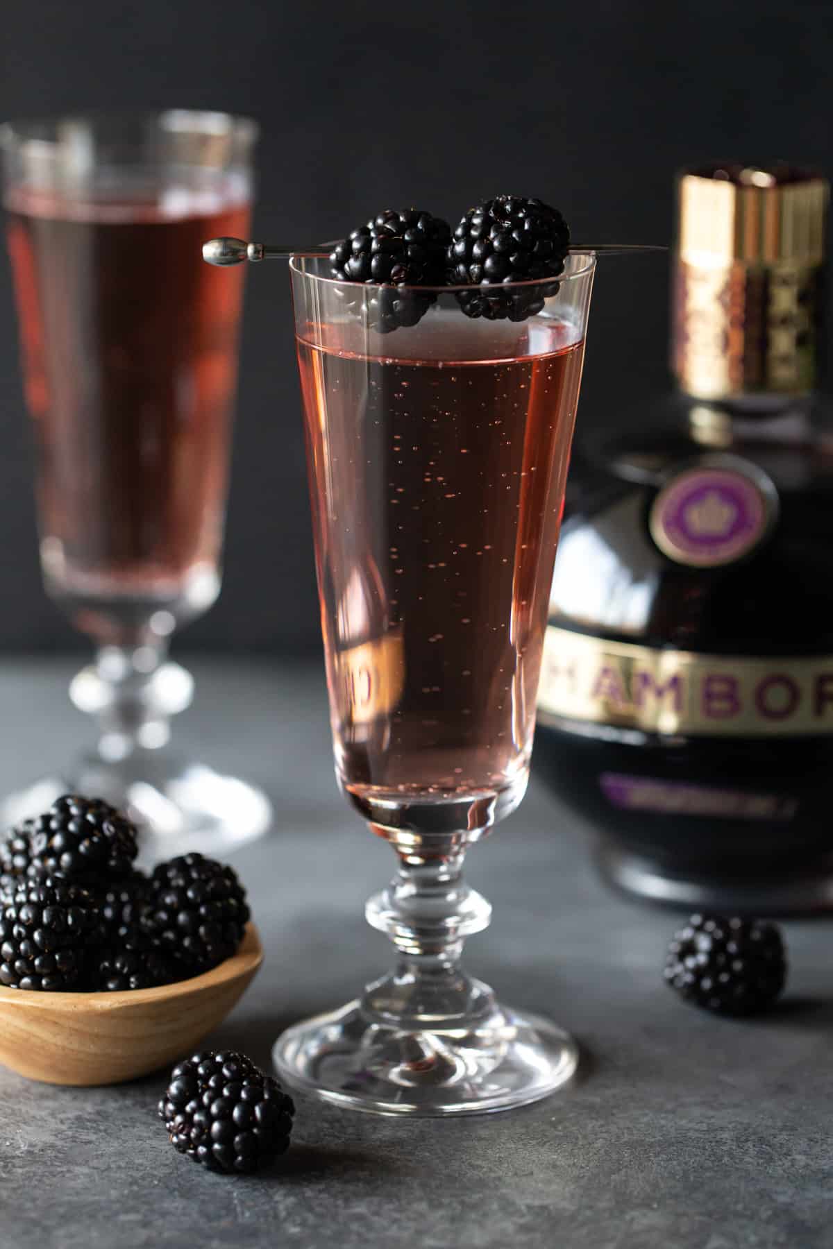 Drinks in footed glasses with blackberries.