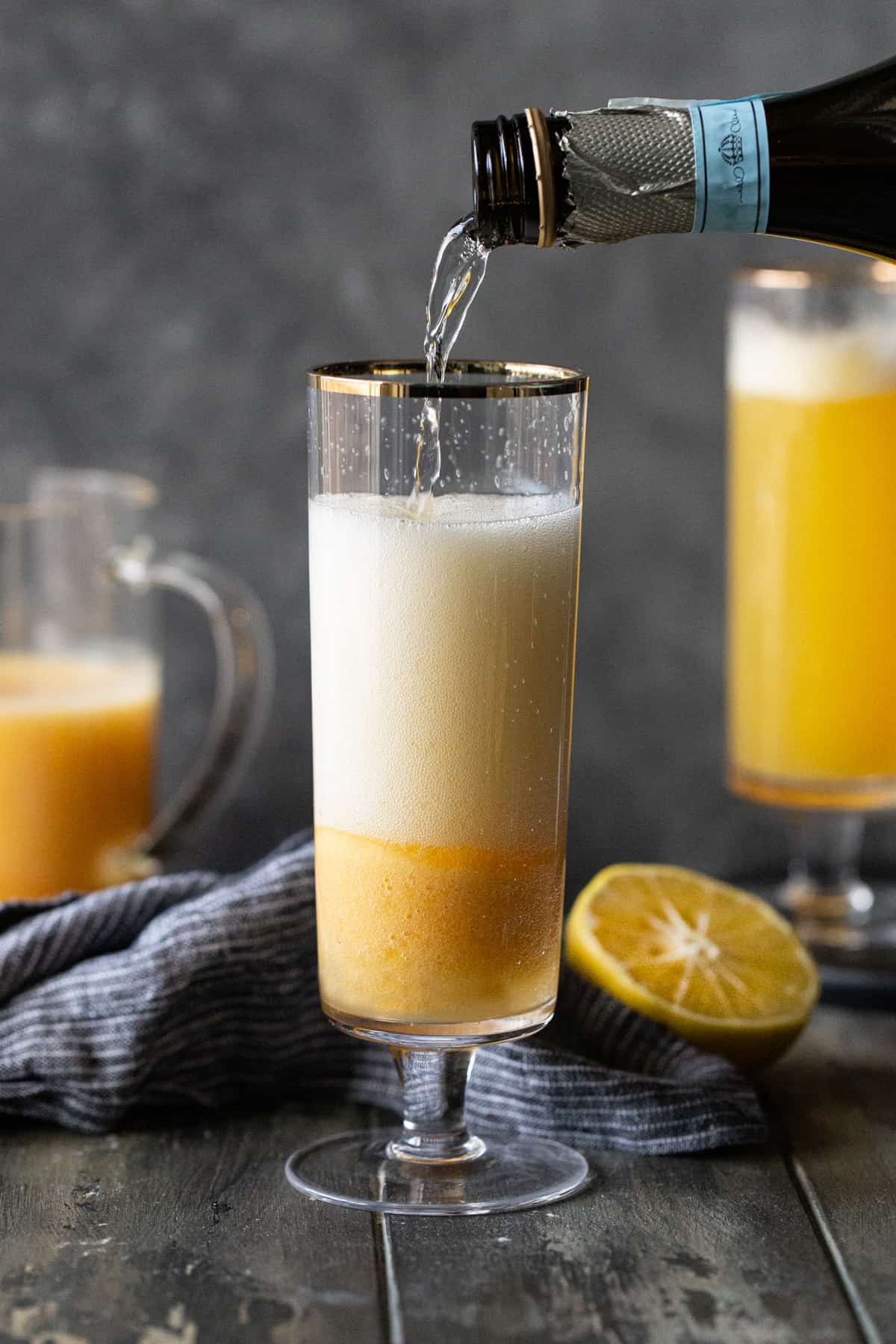 A glass of bellini on a table, with Bellini and Prosecco.