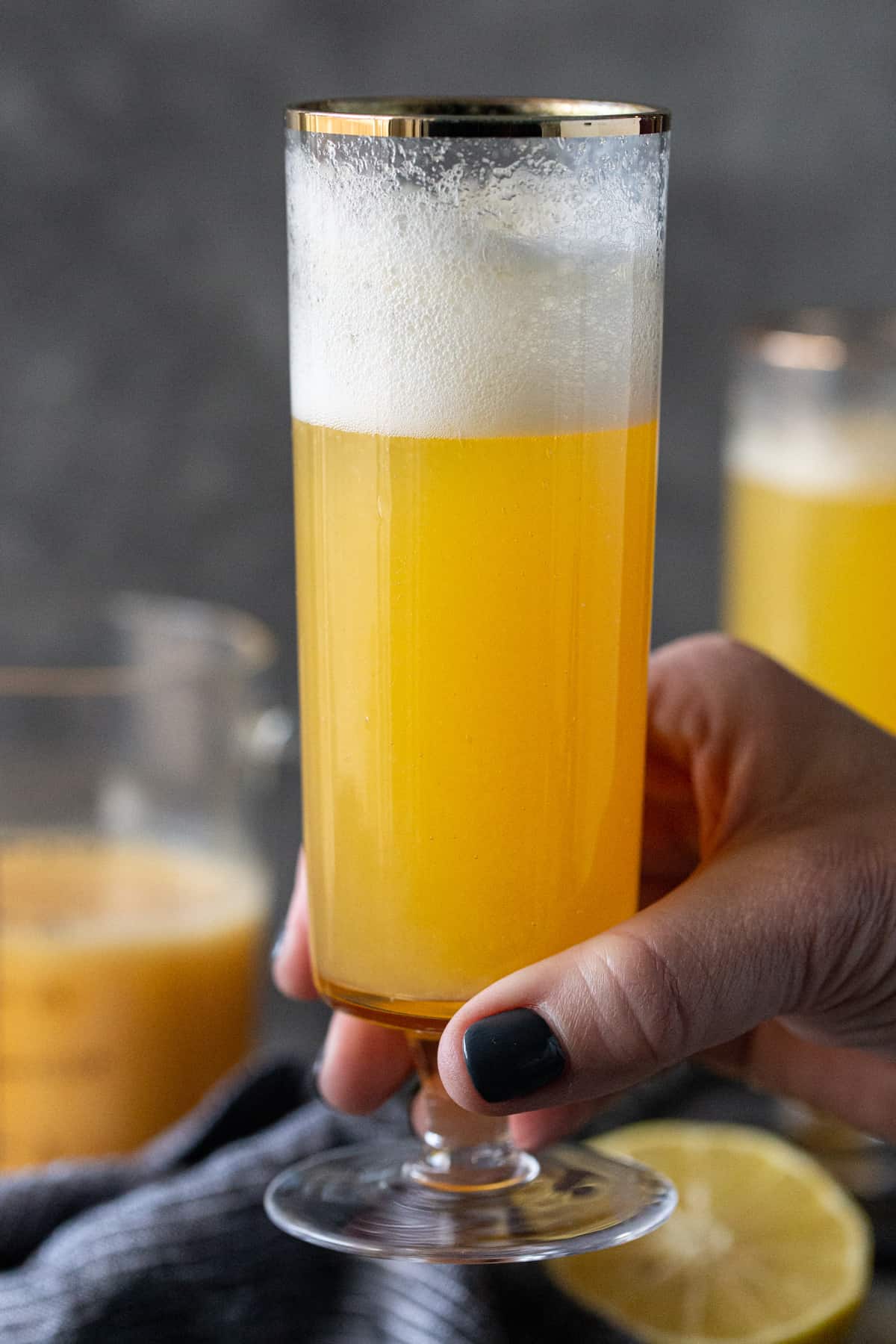 A person holding a glass of bellini on a table, with peach juice and Prosecco.