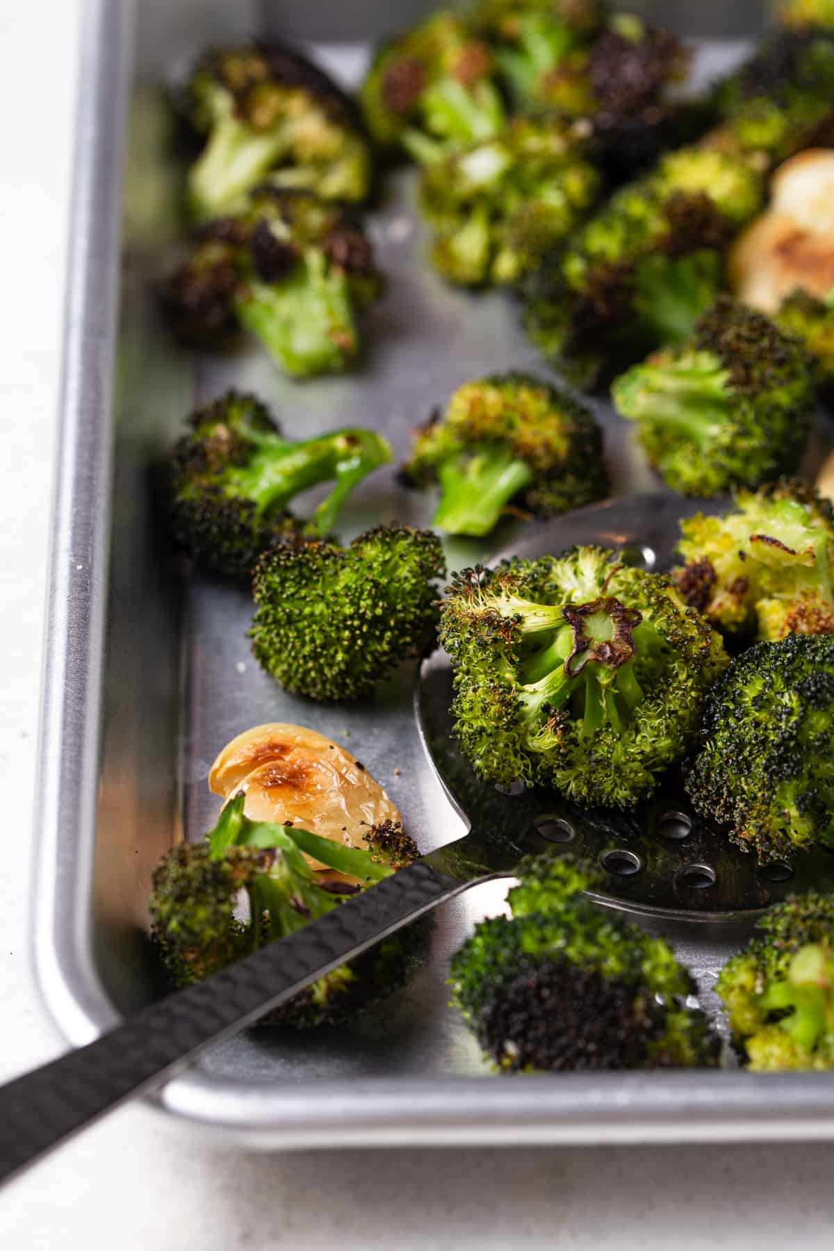 Baked broccoli on a sheet pan with serving spoon. 