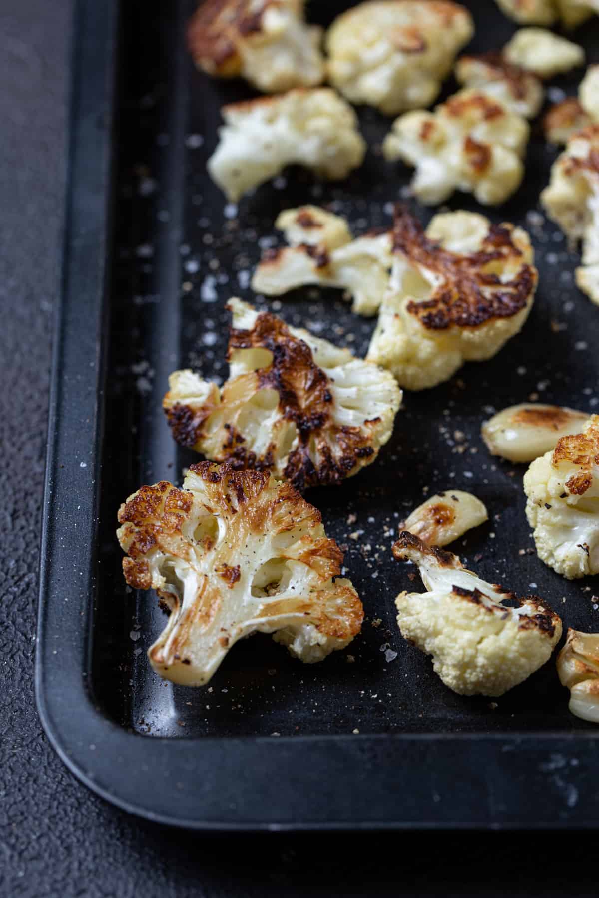 close up of cauliflower on sheet pan with salt and pepper.