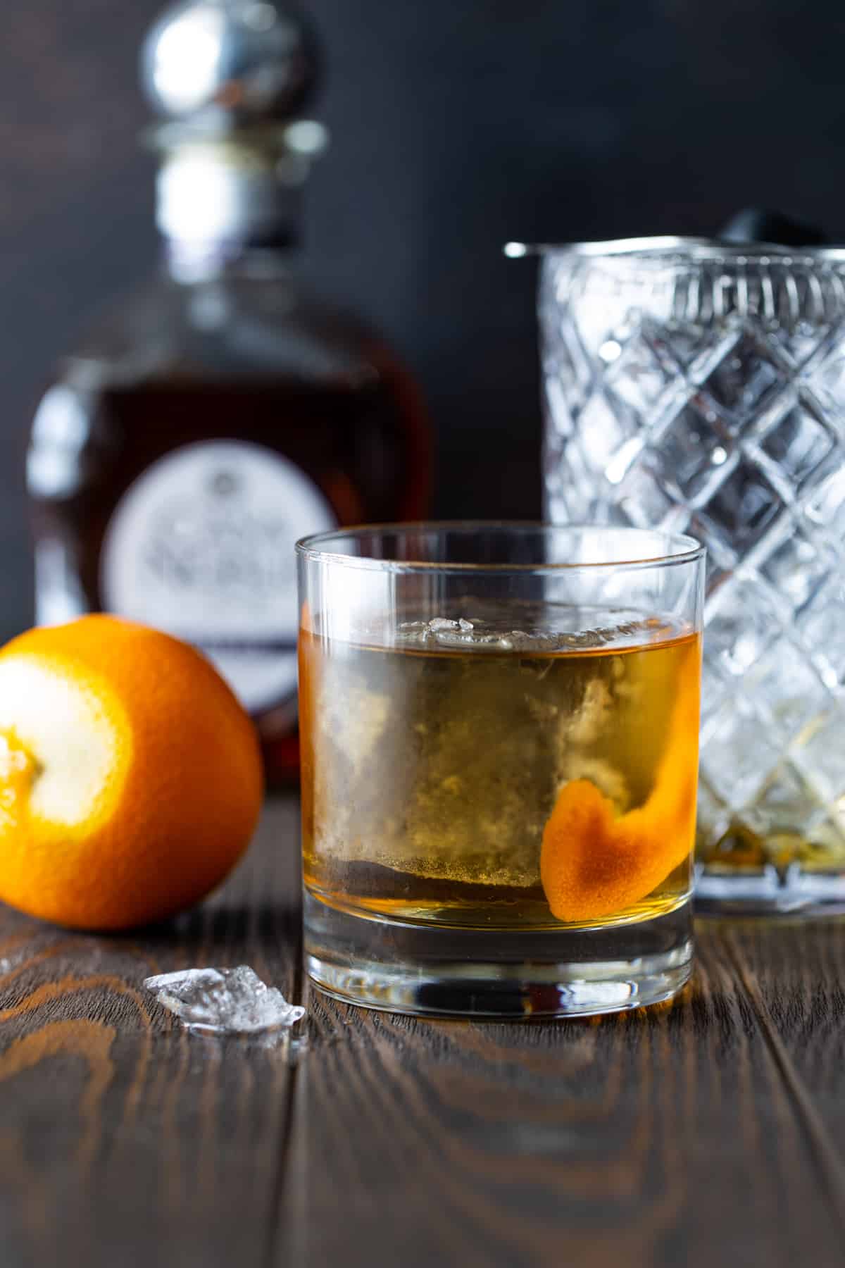 Cocktail in a lowball glass with large ice cube and orange peel. 