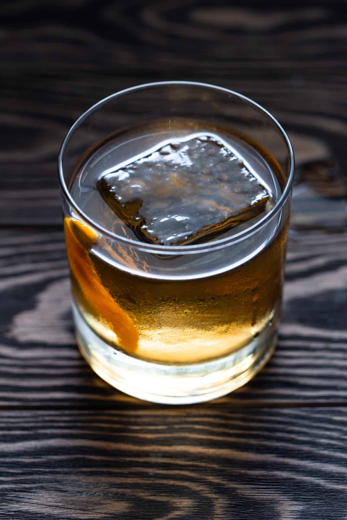 Lowball glass with large ice cube filled with cocktail. 