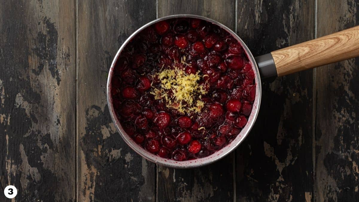 Cranberry sauce in a pot with lemon zest. 