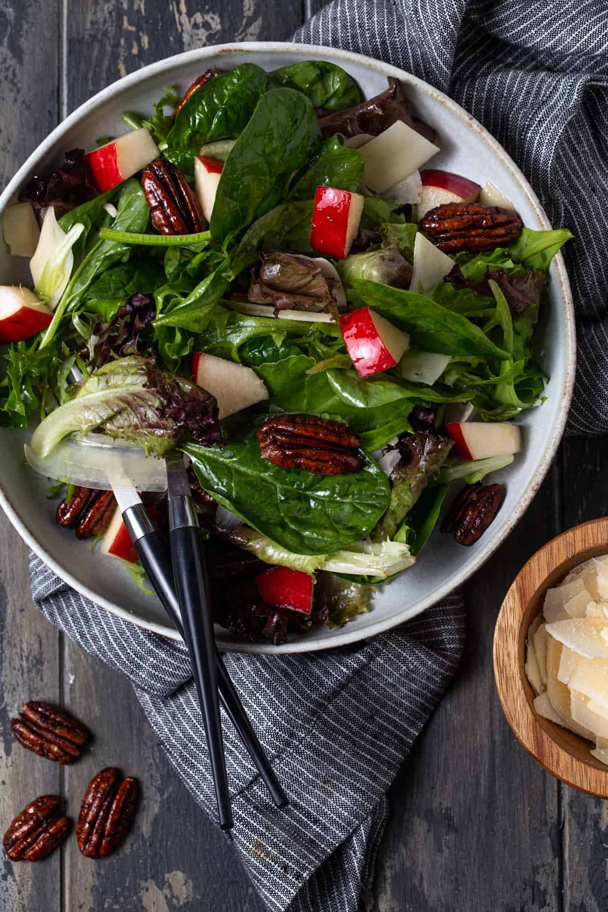 Salad in gray bowl with pears, parmesan cheese and candied pecans. 