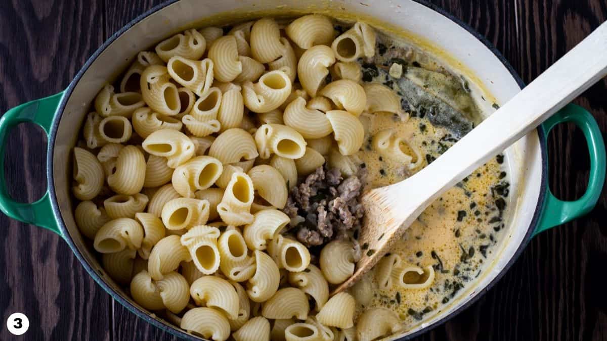 Dutch oven filled with pasta, sausage and pumpkin pasta sauce. 