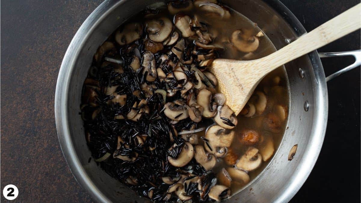 Wild rice, broth and mushrooms in a pan. 
