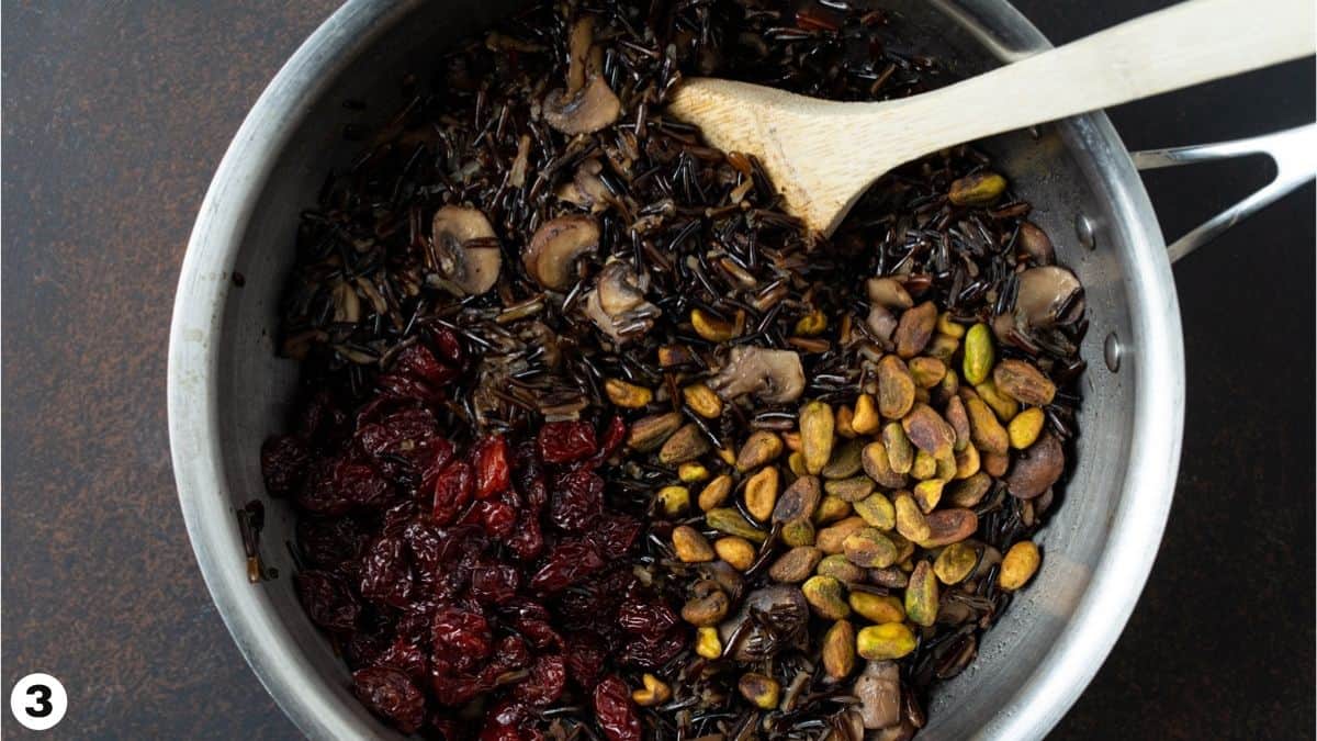 Pistachios, dried cherries, mushrooms and wild rice in pan. 