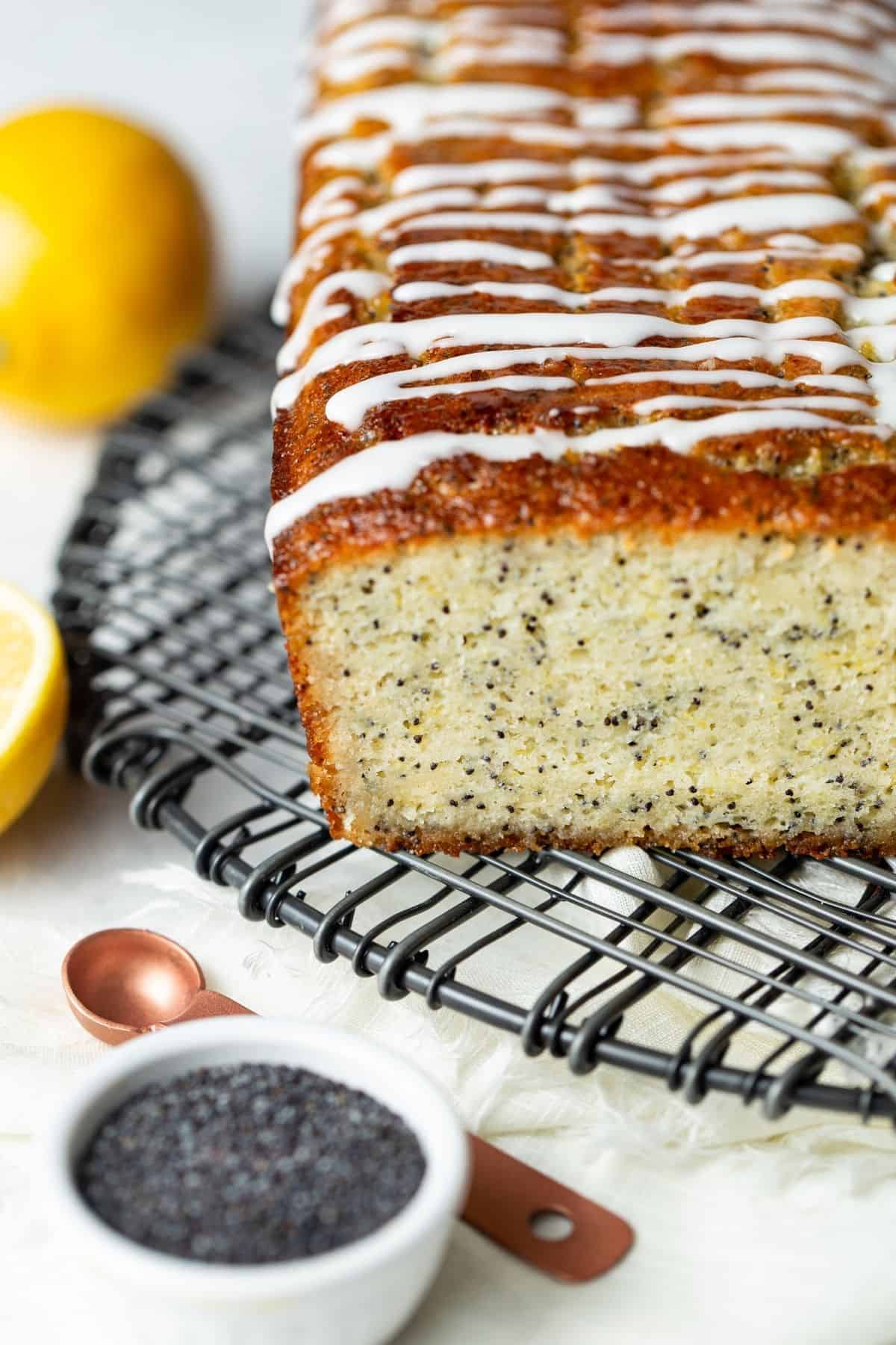 Loaf of lemon poppy seed bread drizzled with glaze on a wire cooling rack