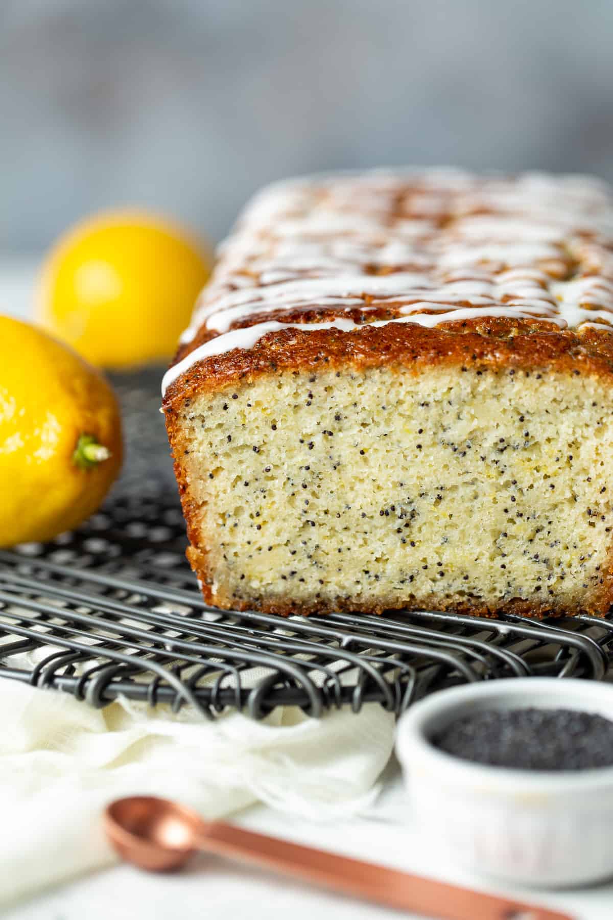 Loaf of lemon poppy seed bread drizzled with glaze on a cooling rack.