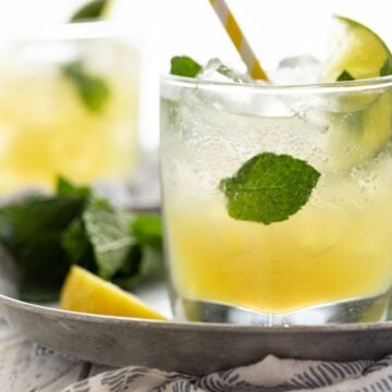 low ball glass fille with drink, mint leaves on silver tray.