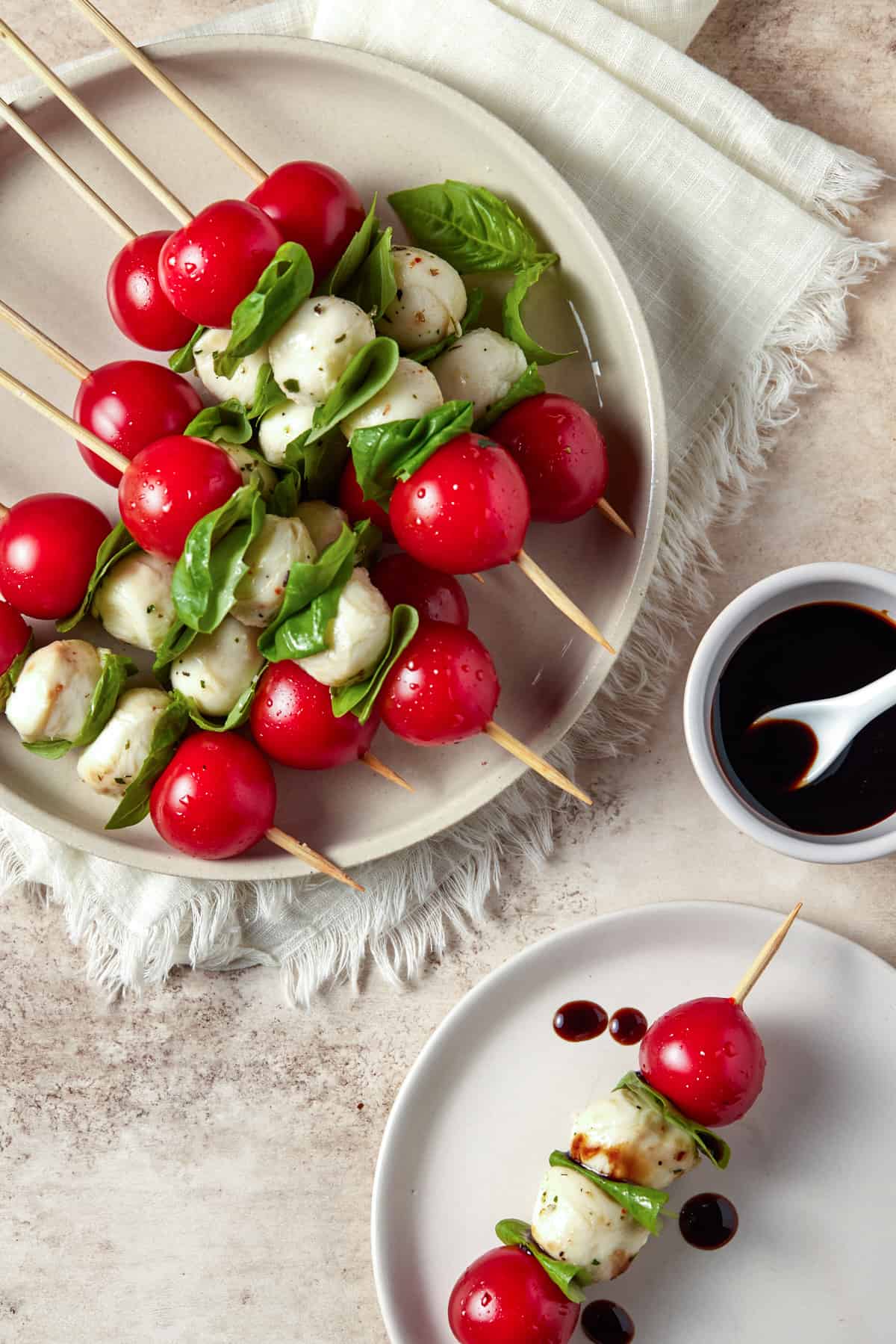 Two plates filled with caprese skewers and drizzled with balsamic glaze. 