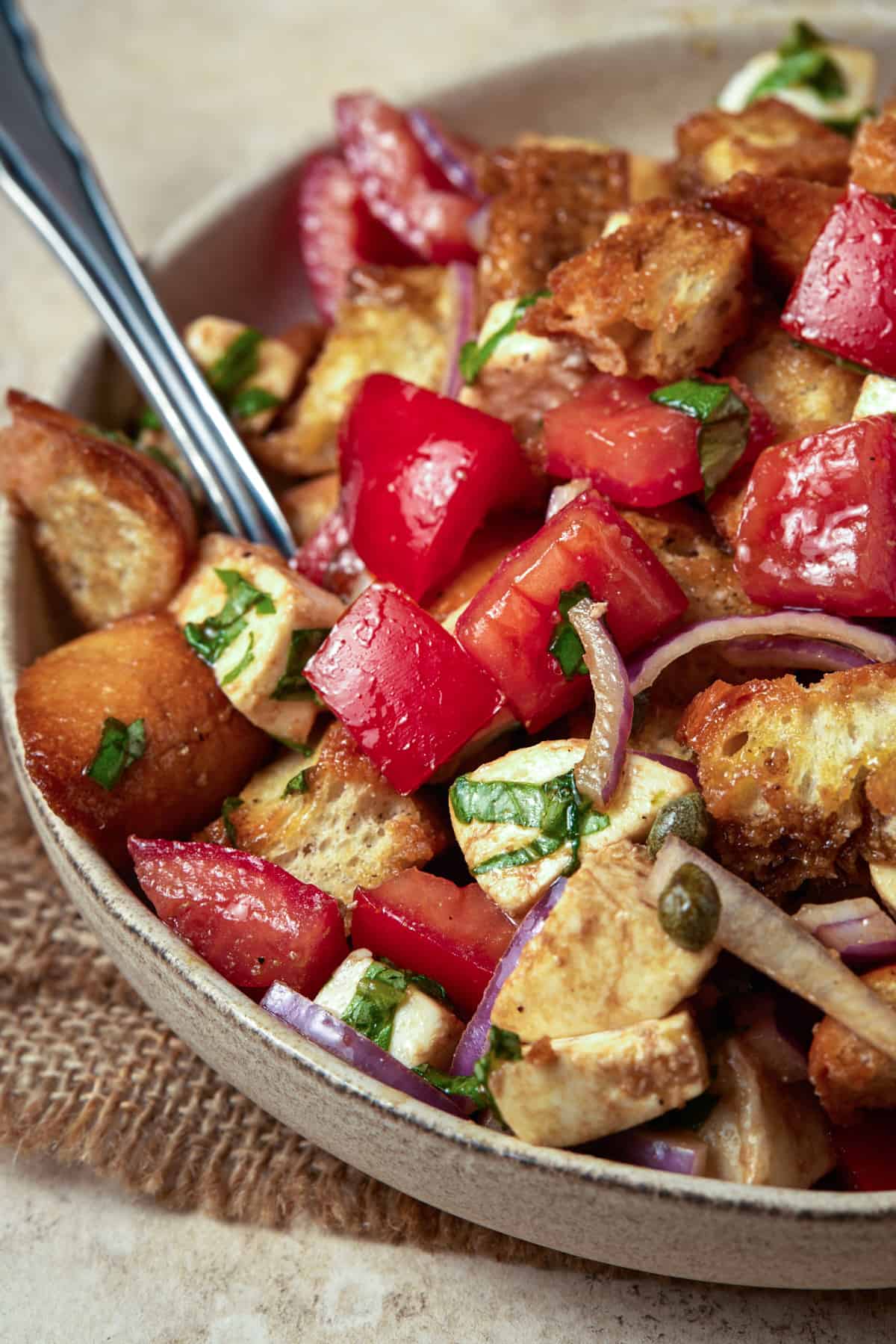 Panzanella salad in a ceramic bowl with a spoon. 