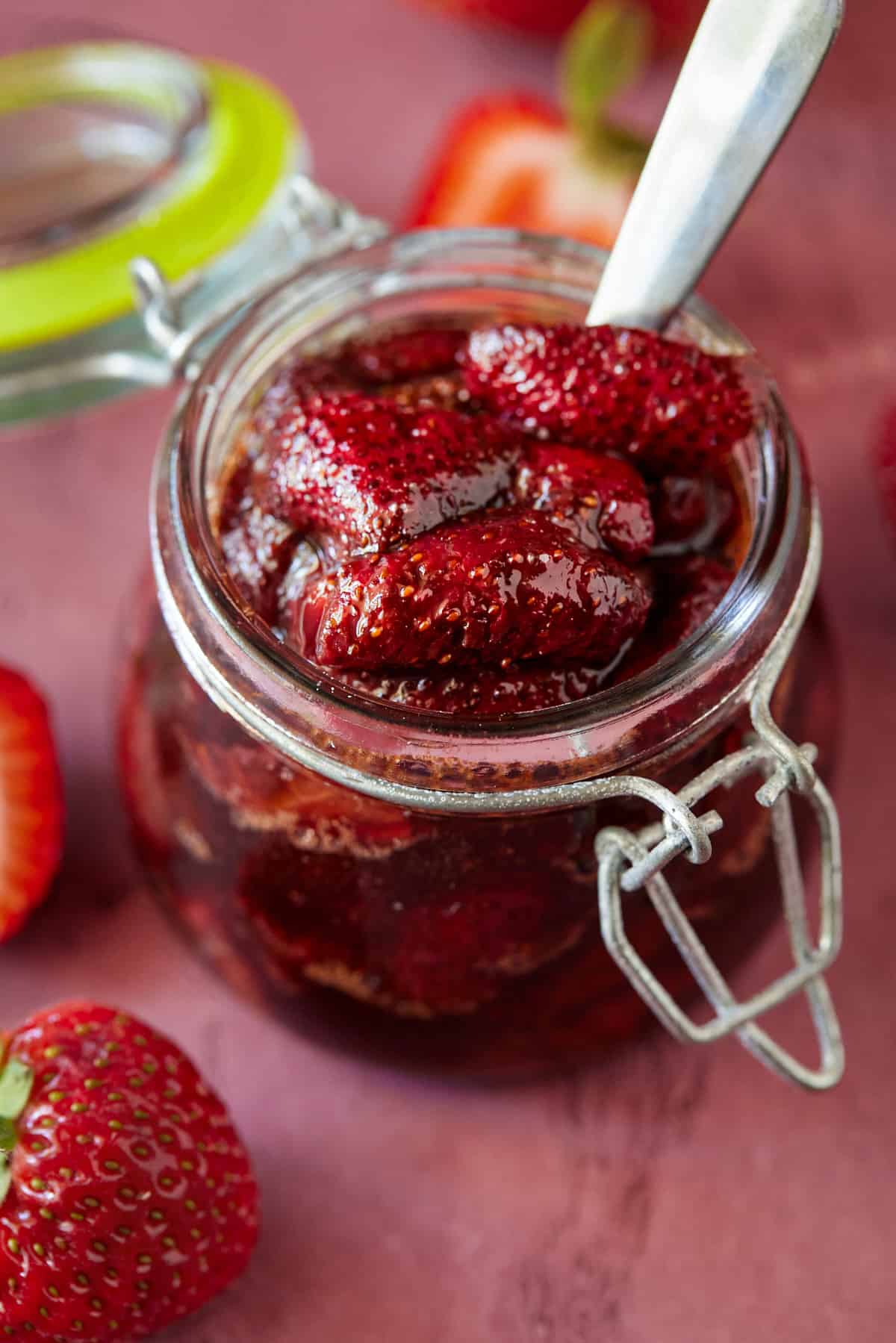 Glass jar of homemade strawberry sauce with a spoon. 