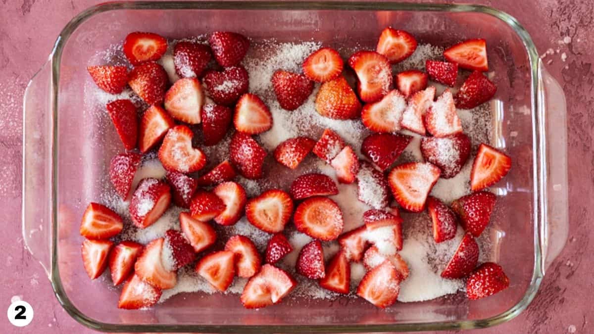 Chopped strawberries sprinkled with sugar in glass baking dish. 