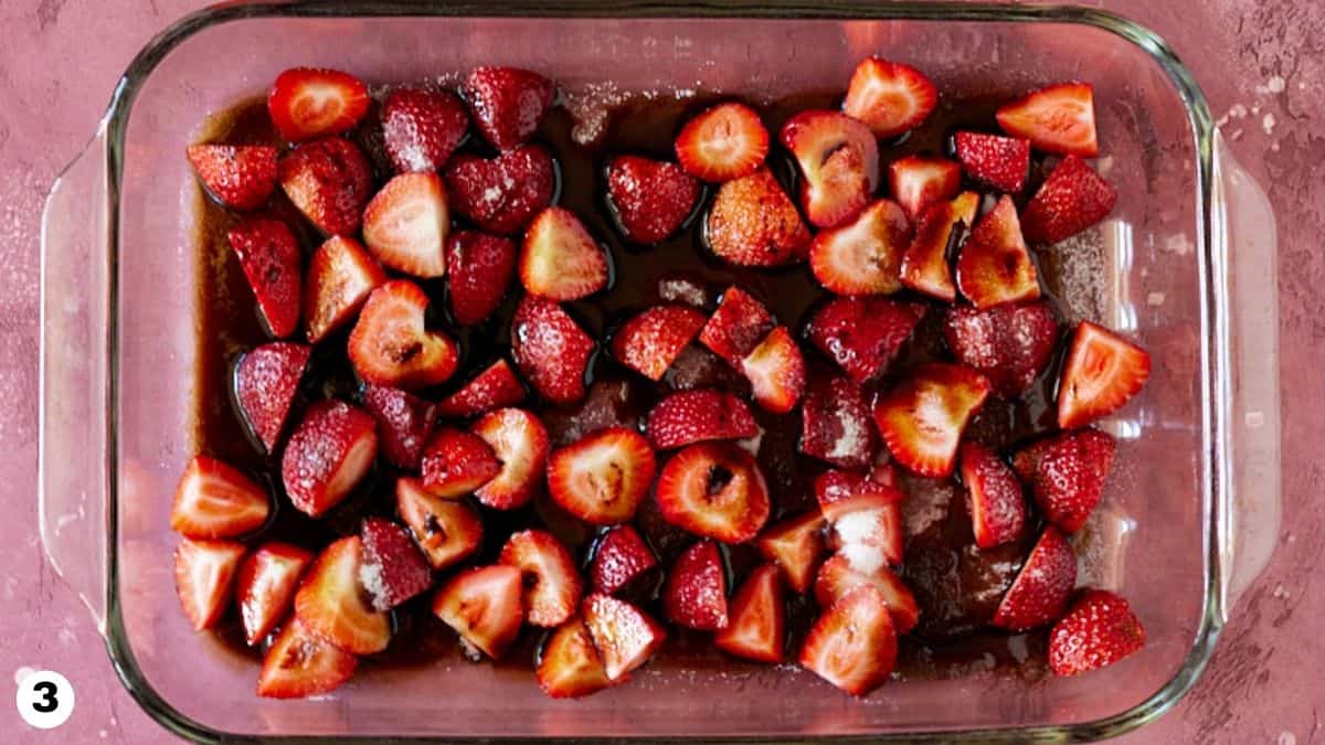 Balsamic vinegar drizzled over chopped strawberries in glass baking dish. 