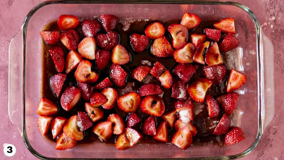 Balsamic vinegar drizzled over chopped strawberries in glass baking dish. 