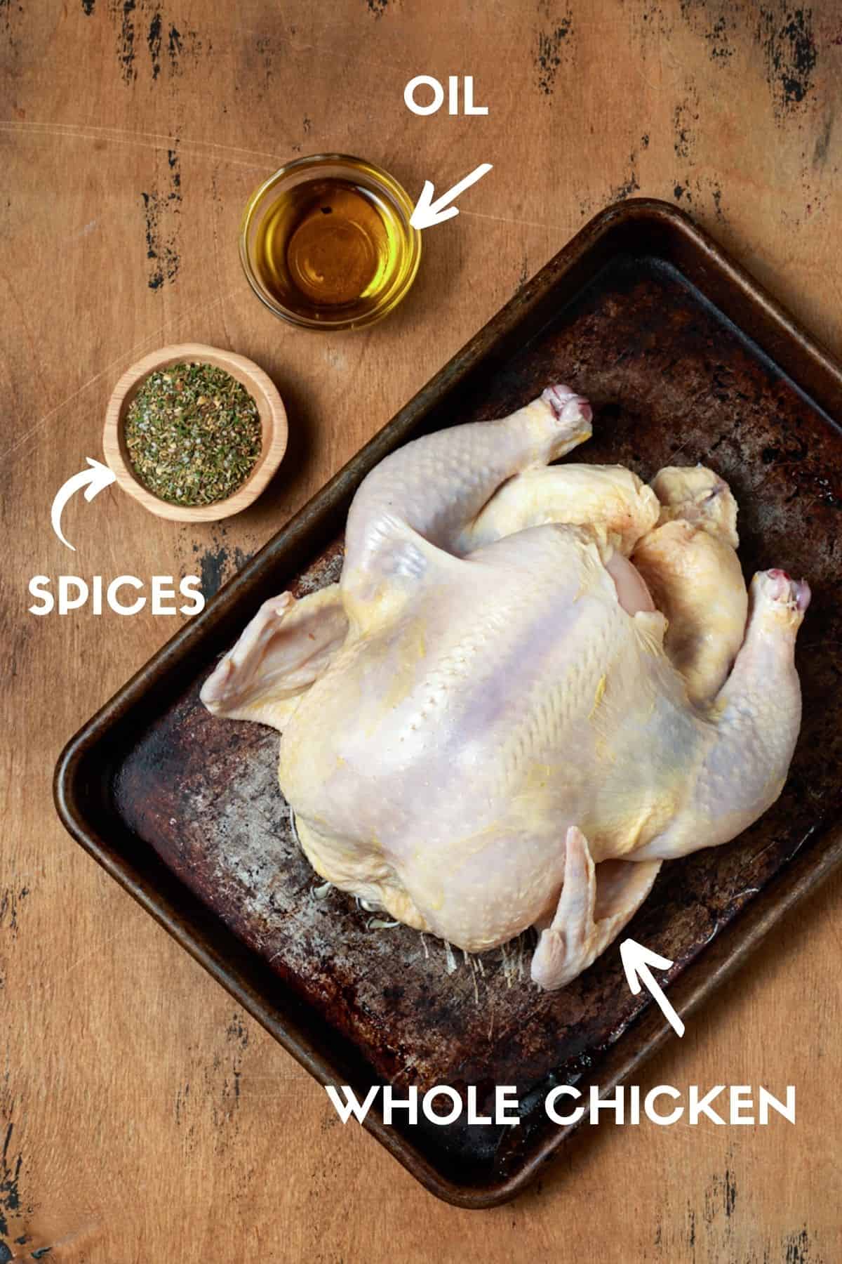 Whole chicken on a sheet pan with bowls of oil and seasoning. 