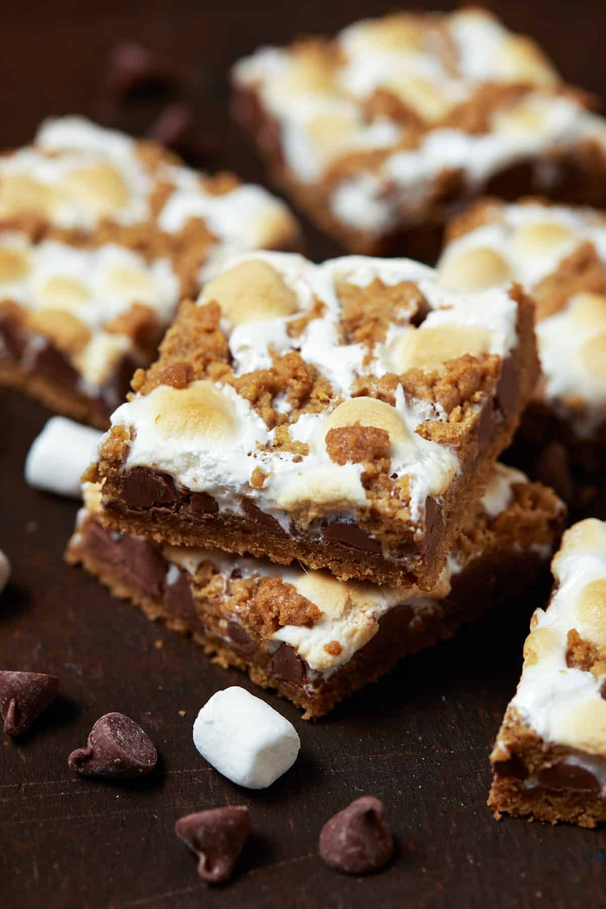 A short stack of baked s'mores bars on a dark wood board. 