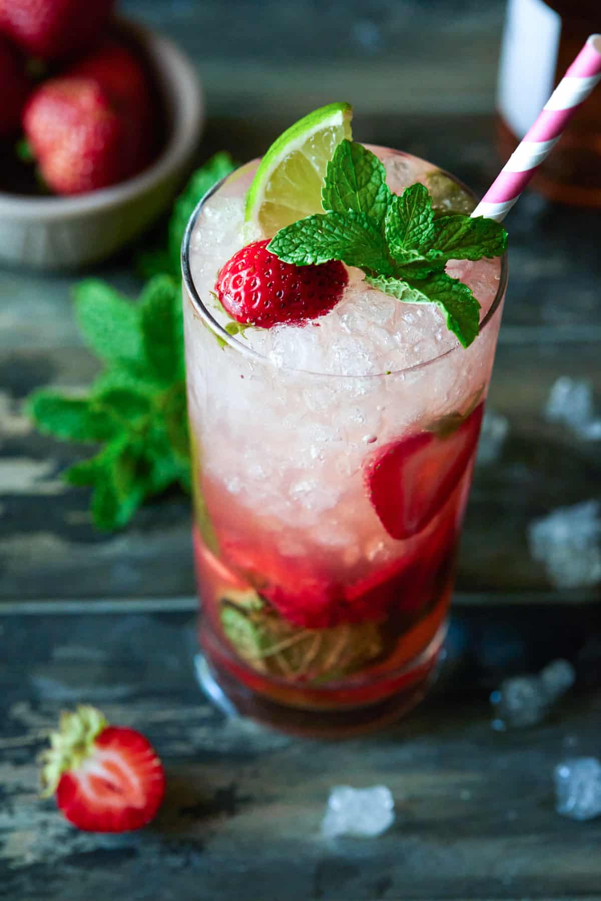 Strawberry mojito in a highball glass garnished with fresh lime, strawberry and mint leaves. 