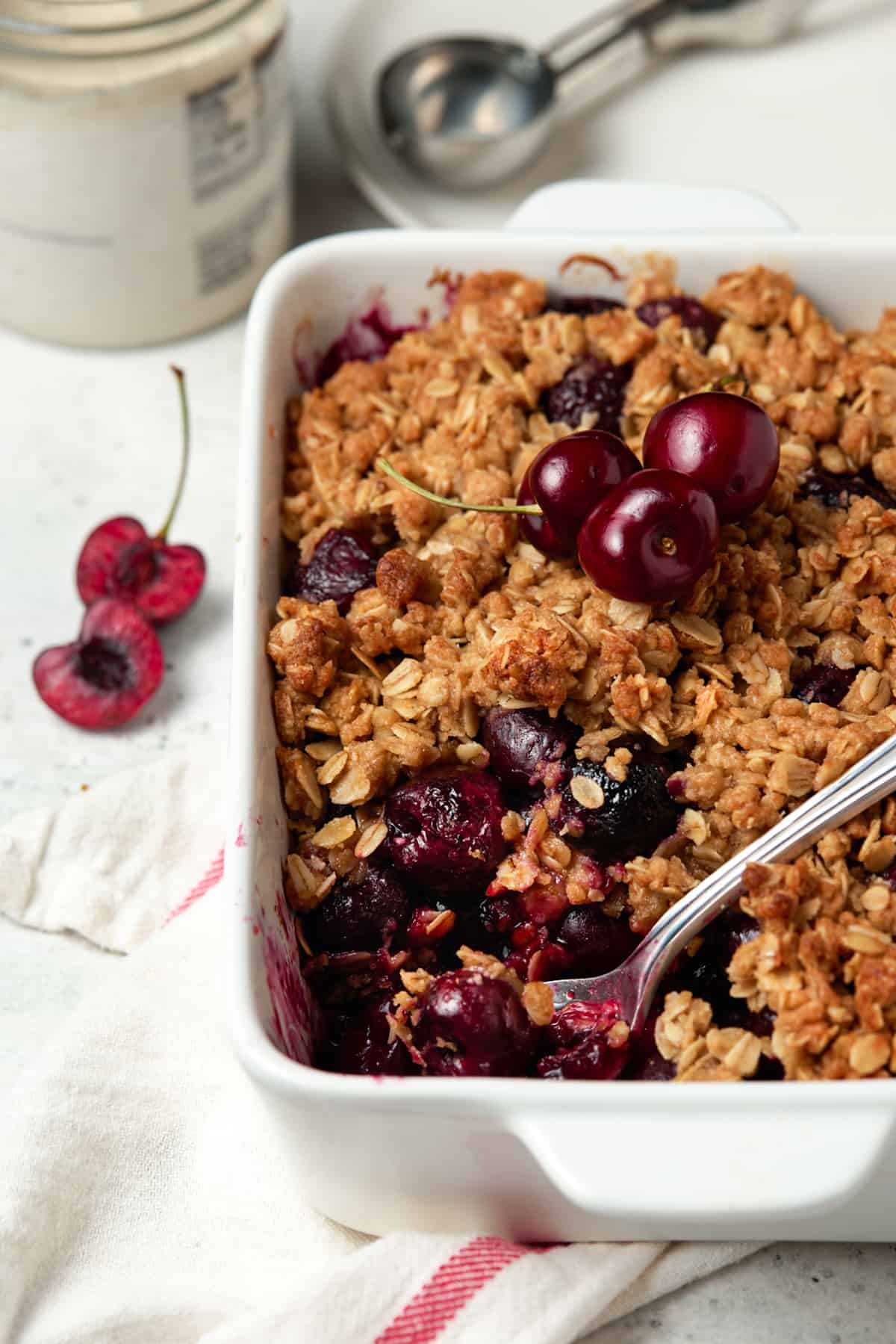 White casserole dish of baked cherry crisp with serving removed. 