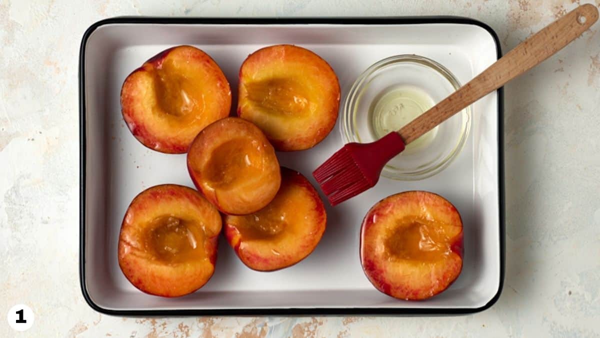 Peach halves in a white enamel tray. 