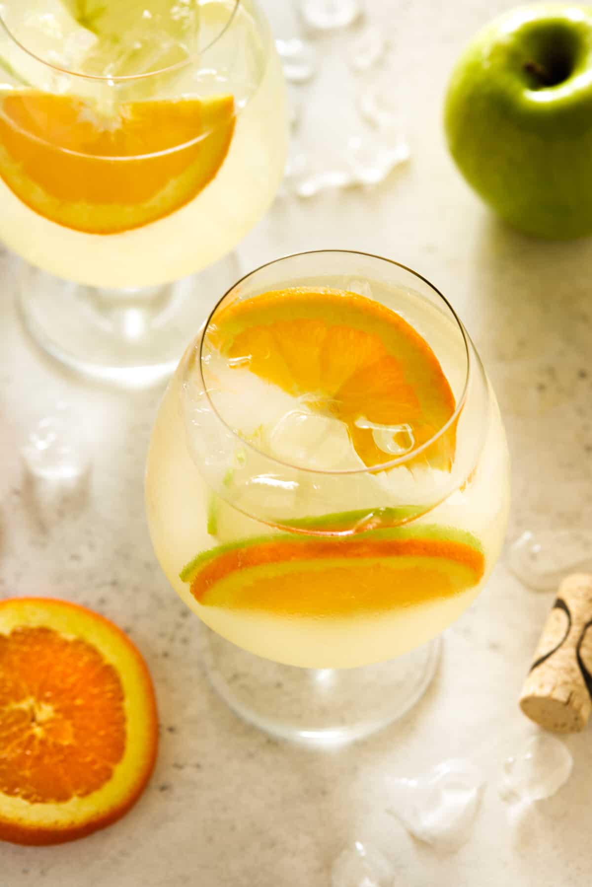 large glasses filled with lemonade and fresh orange and apple slices.