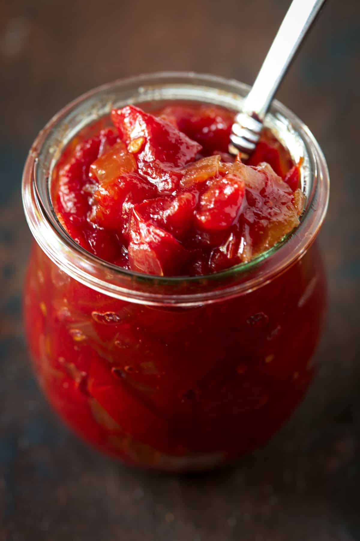 Glass jar of tomato jam with a spoon. 