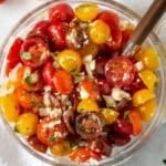 Cherry tomato salad in a glass bowl with a white linen napkin.