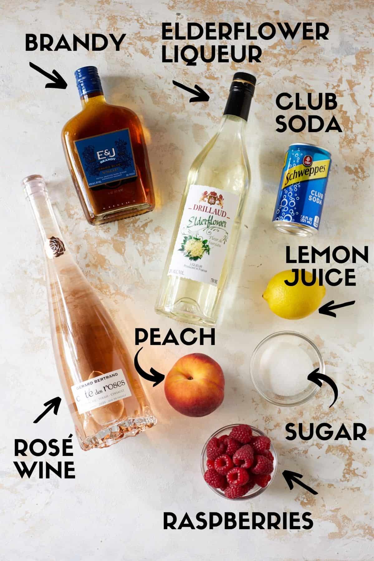 Rosé sangria ingredients, including rosé wine, elderflower liqueur, brandy, peaches and raspberries. 