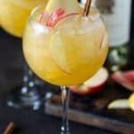 Glass of apple cider sangria garnished with pear and apple slices.