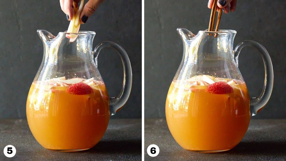 Hand adding sliced apples, pears and cinnamon sticks to a pitcher. 