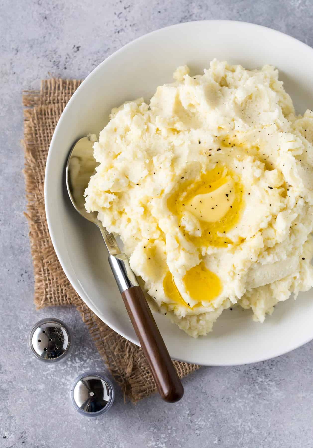 Mashed potatoes in white bowl with melted butter on top. 