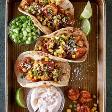 shrimp tacos on tray with green onions and chipotle cream.