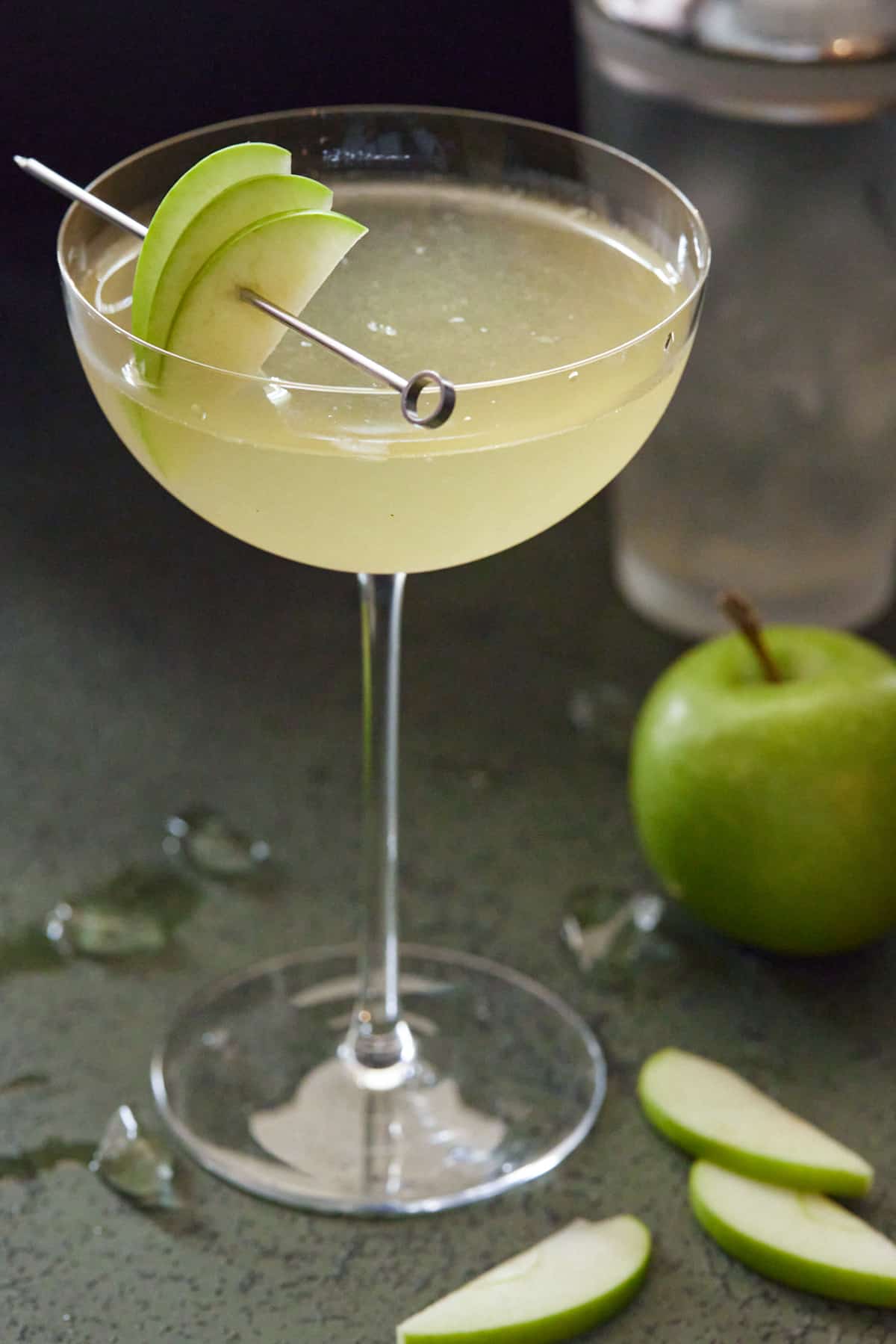 Apple martini in tall coupe glass with fresh apples.