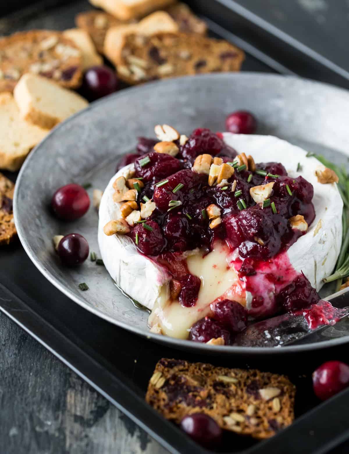 Baked brie with cranberries in silver dish. 