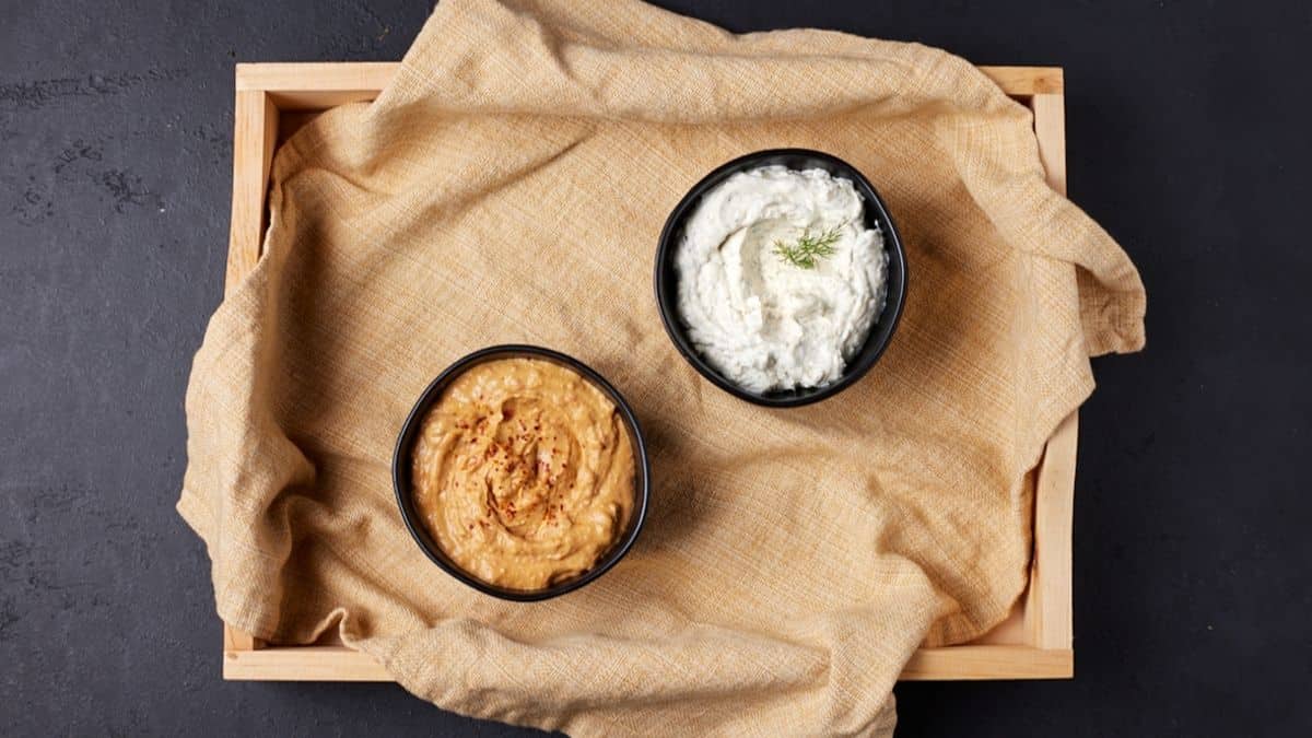 Wooden tray with two bowls of dip. 