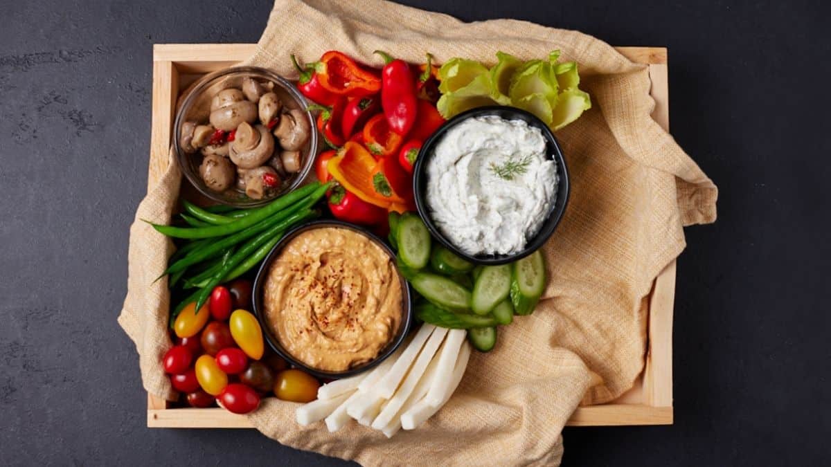 Wooden tray filled with veggies and dips.