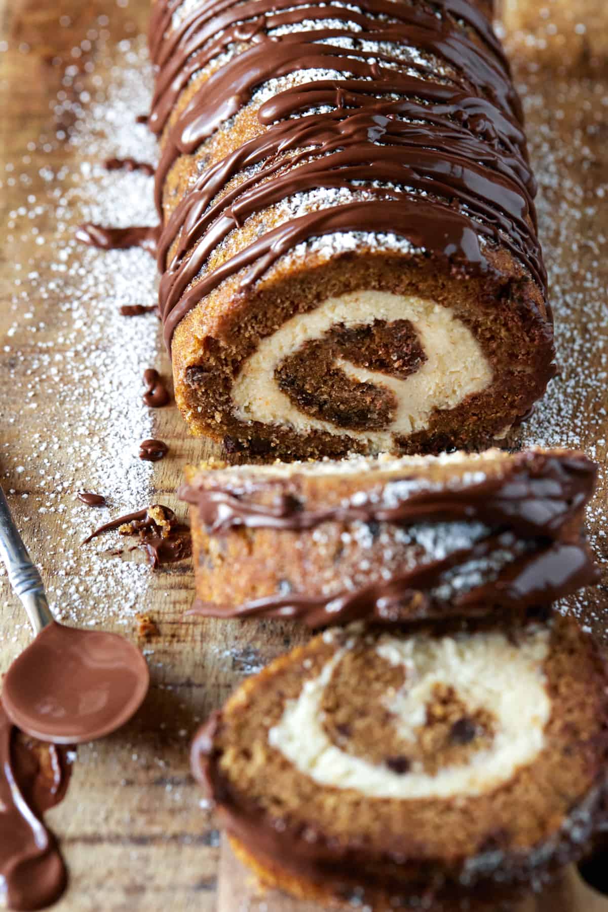 Slices of pumpkin chocolate swiss roll cake on a wooden cutting board. 