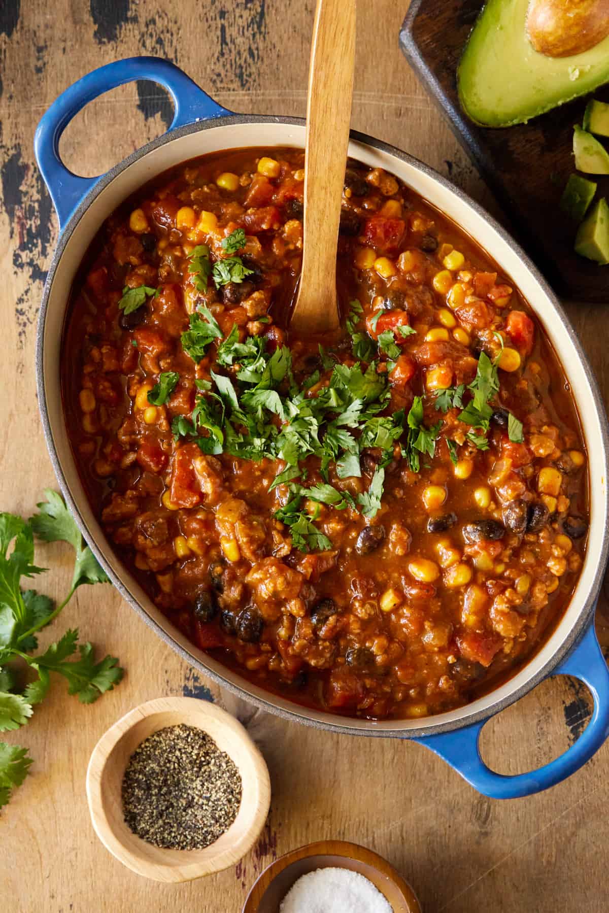 Chili in dutch oven with cilantro and serving spoon.