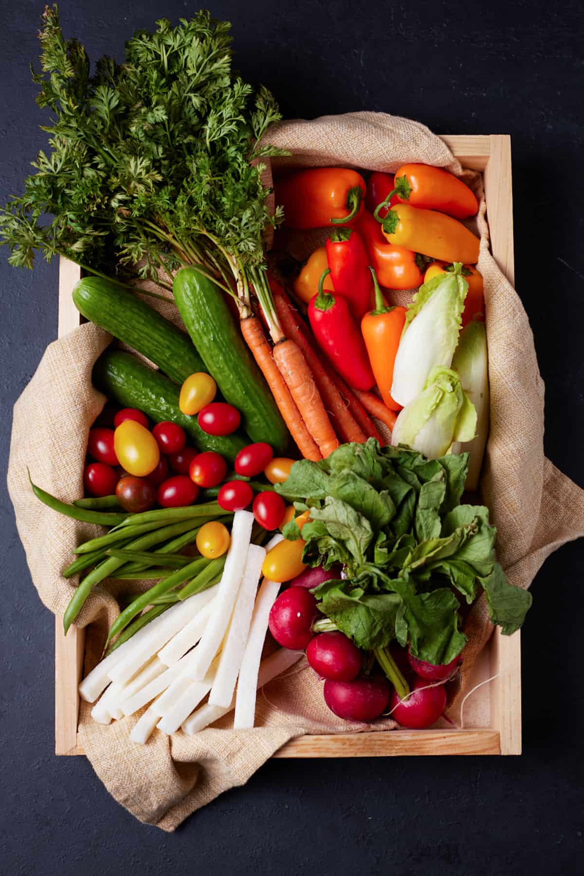 A wooden box filled with colorful vegetables. 